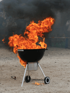 Dreibeiniger Holzkohlegrill aus dem es lichterloh brennt