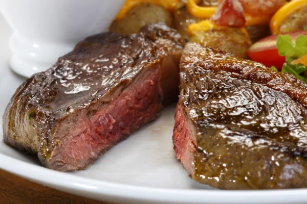 Mittig aufgeschnittenes Steak, lecker angebraten auf schön dekoriertem Teller