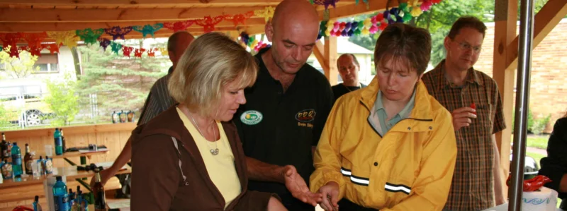 Grillmeister Sven Dörge in seinem Grillkurs hilft 2 Teilnehmerinnen bei der Zubereitung von Gemüse